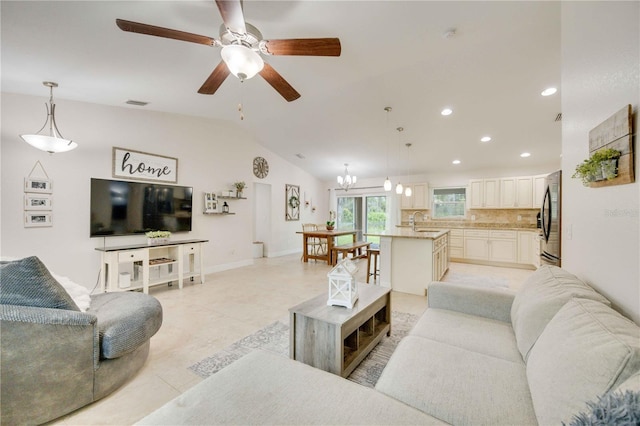 tiled living room featuring sink, ceiling fan with notable chandelier, and lofted ceiling