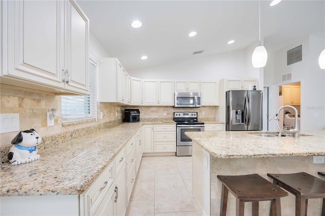 kitchen featuring pendant lighting, white cabinets, sink, vaulted ceiling, and stainless steel appliances