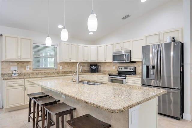 kitchen with pendant lighting, stainless steel appliances, vaulted ceiling, and a kitchen island with sink