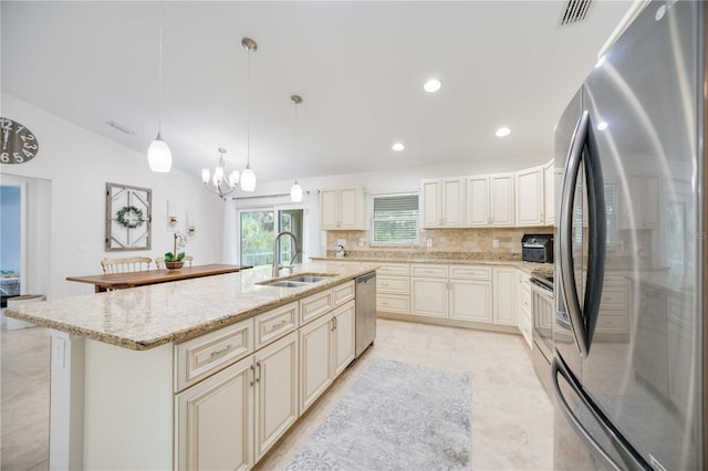 kitchen featuring backsplash, a kitchen island with sink, sink, hanging light fixtures, and appliances with stainless steel finishes