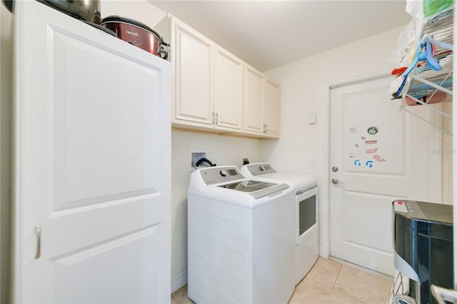 clothes washing area featuring cabinets, light tile patterned flooring, and washing machine and clothes dryer