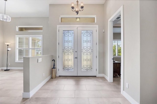 entryway featuring a healthy amount of sunlight, light tile patterned flooring, an inviting chandelier, and french doors