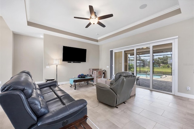 living room with ceiling fan, a raised ceiling, and ornamental molding