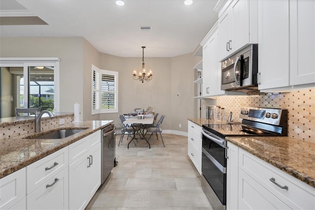 kitchen featuring dark stone countertops, white cabinets, stainless steel appliances, and sink