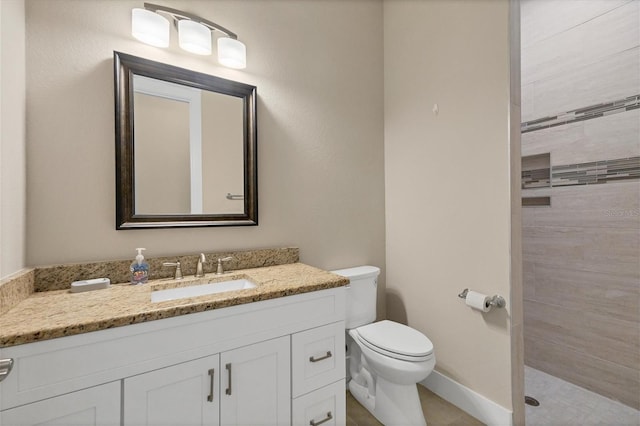 bathroom with tiled shower, vanity, and toilet