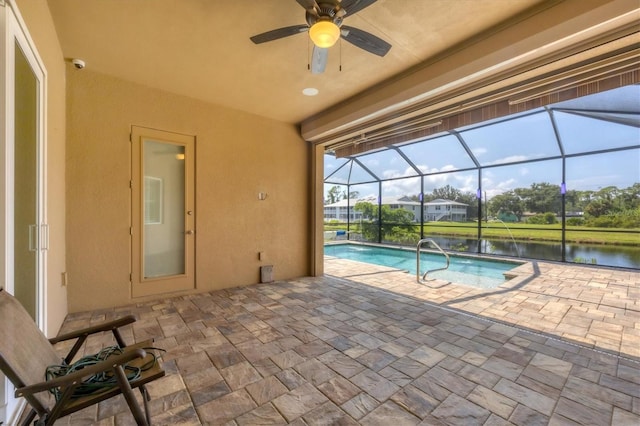 view of swimming pool with glass enclosure, a water view, ceiling fan, and a patio area