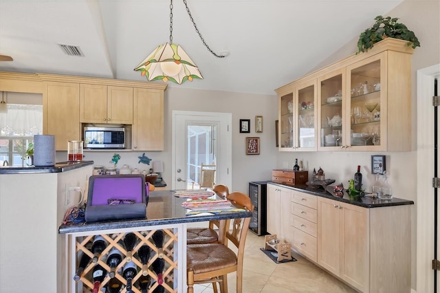 kitchen featuring beverage cooler, vaulted ceiling, hanging light fixtures, light tile patterned floors, and light brown cabinetry