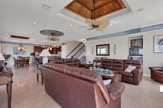 living room featuring a raised ceiling, ornamental molding, and ceiling fan