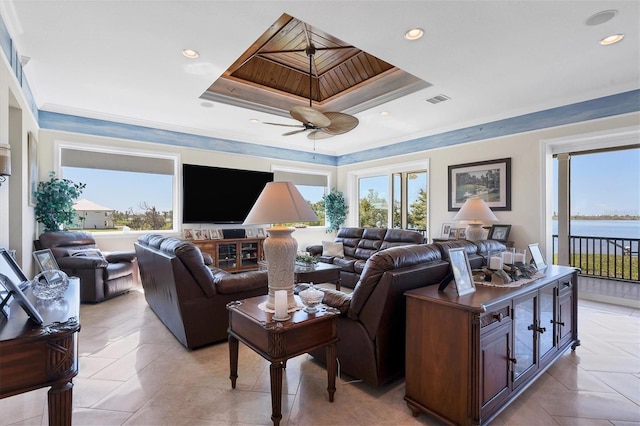 tiled living room with ornamental molding, a tray ceiling, and ceiling fan