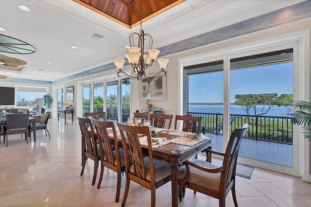 tiled dining area featuring a healthy amount of sunlight, a water view, ornamental molding, and an inviting chandelier