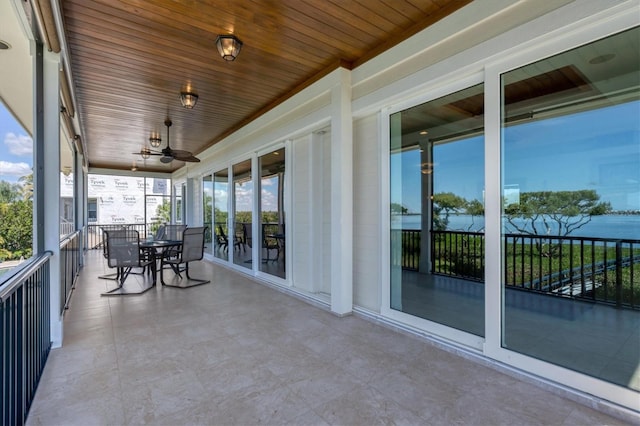 sunroom / solarium featuring a water view, ceiling fan, and wooden ceiling