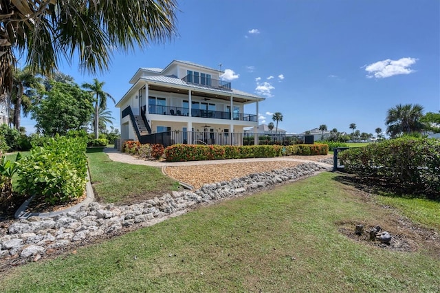 rear view of house with a balcony and a yard