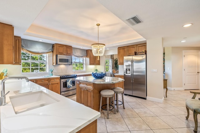 kitchen featuring a healthy amount of sunlight, a kitchen island, pendant lighting, and stainless steel appliances