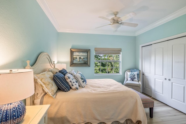 bedroom featuring light wood-type flooring, ornamental molding, ceiling fan, and a closet