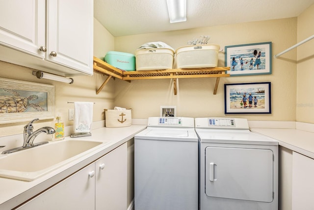 laundry room featuring a textured ceiling, sink, washing machine and clothes dryer, and cabinets