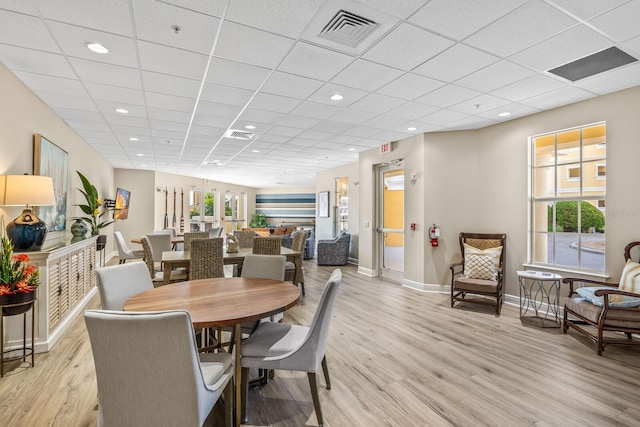 dining space featuring a paneled ceiling and light hardwood / wood-style flooring