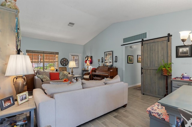 living area with lofted ceiling, a barn door, visible vents, and wood tiled floor