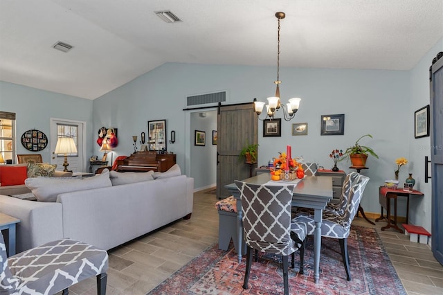 dining space with light wood-type flooring, vaulted ceiling, a chandelier, and a barn door