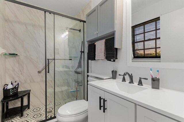 bathroom featuring toilet, vanity, and a marble finish shower