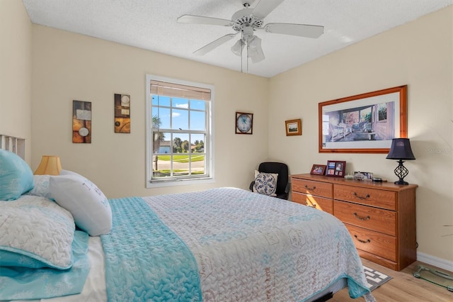 bedroom featuring light wood-type flooring, ceiling fan, and a textured ceiling