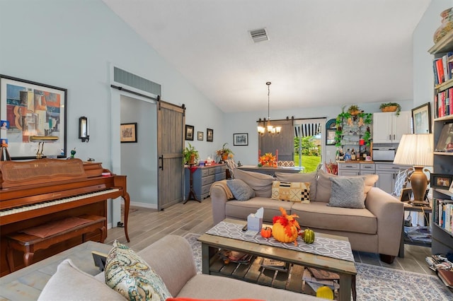 living area featuring a notable chandelier, visible vents, light wood-style flooring, a barn door, and high vaulted ceiling