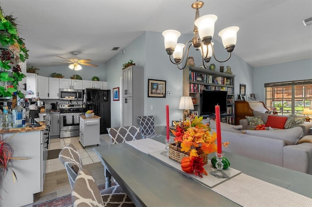 dining space with light tile patterned floors, lofted ceiling, visible vents, and ceiling fan with notable chandelier