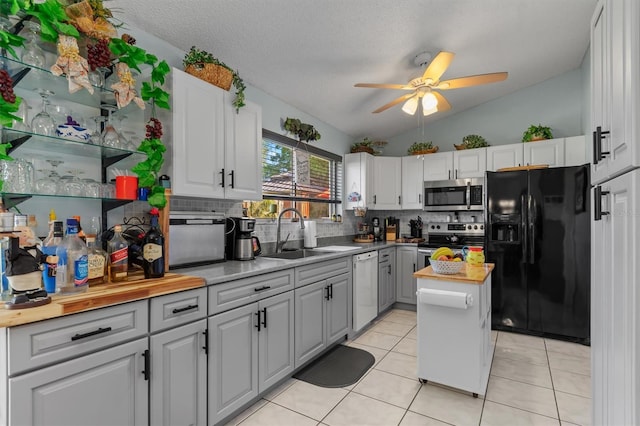 kitchen featuring butcher block counters, a sink, vaulted ceiling, appliances with stainless steel finishes, and backsplash