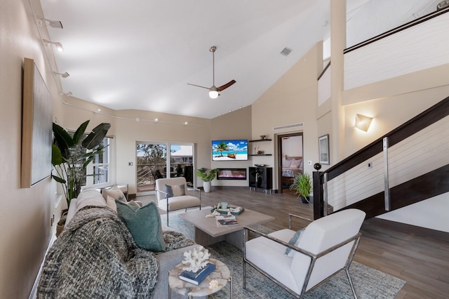 living room with ceiling fan, hardwood / wood-style floors, and high vaulted ceiling