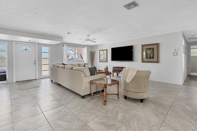 living room with ceiling fan and a textured ceiling