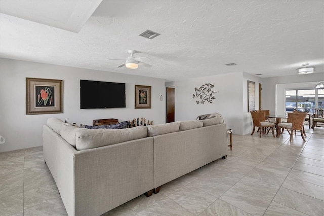 living room with ceiling fan and a textured ceiling