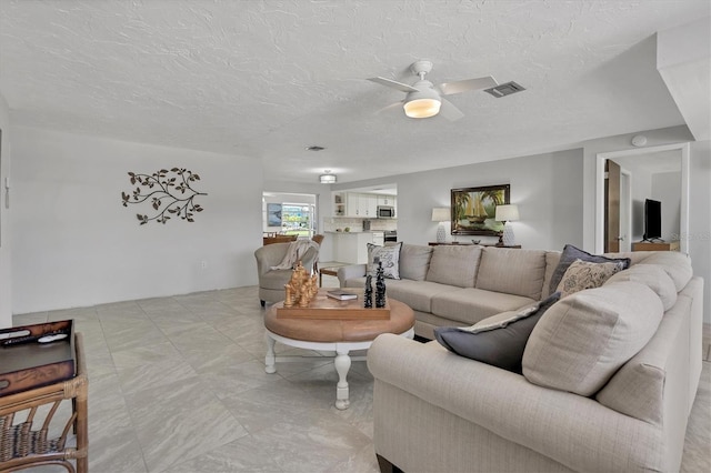 living room featuring ceiling fan and a textured ceiling