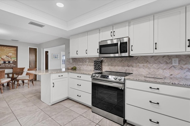 kitchen featuring kitchen peninsula, backsplash, stainless steel appliances, and white cabinetry