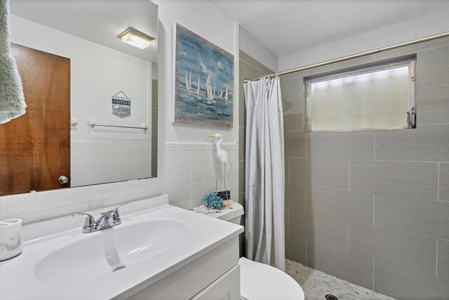 bathroom featuring a shower with curtain, vanity, toilet, and tile walls