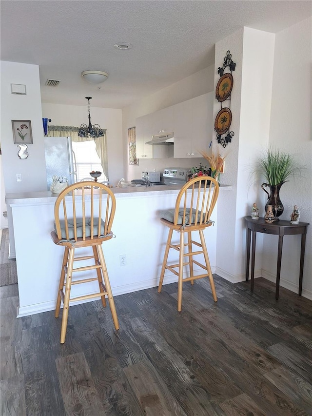 kitchen with kitchen peninsula, a kitchen breakfast bar, white refrigerator, dark hardwood / wood-style floors, and white cabinetry