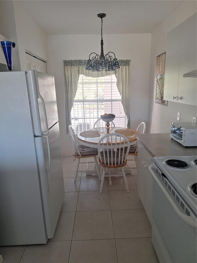 kitchen featuring white appliances, decorative light fixtures, a notable chandelier, white cabinets, and light tile patterned flooring