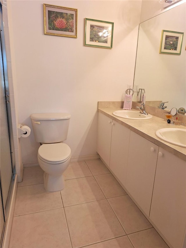 bathroom with tile patterned flooring, vanity, a shower with shower door, and toilet