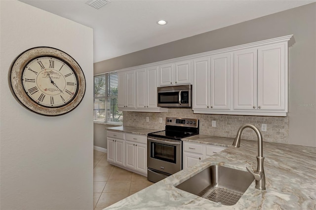 kitchen featuring light stone counters, sink, white cabinetry, backsplash, and appliances with stainless steel finishes