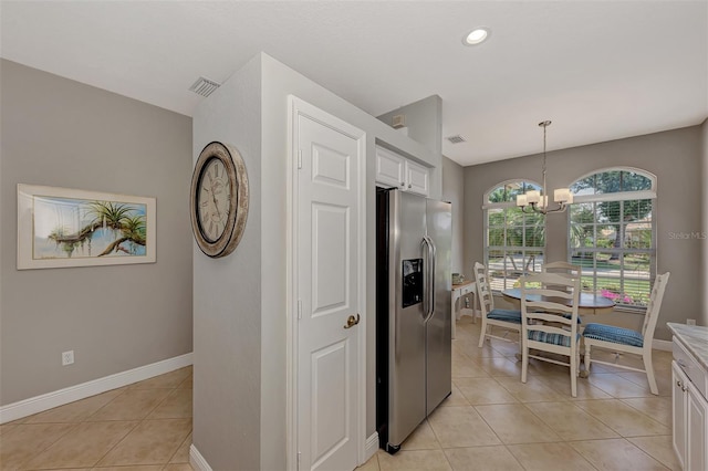 kitchen with pendant lighting, a chandelier, stainless steel refrigerator with ice dispenser, white cabinetry, and light tile patterned floors