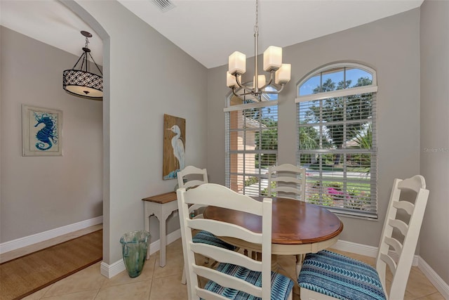 tiled dining room with lofted ceiling and a notable chandelier