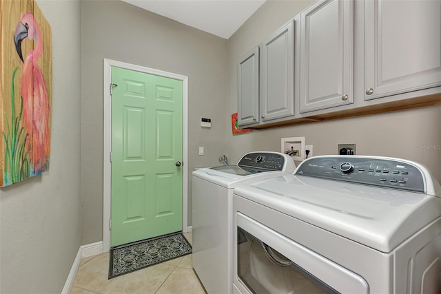 laundry area with cabinets, light tile patterned floors, and washer and clothes dryer