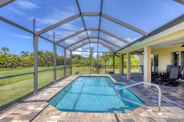 view of pool with glass enclosure, a lawn, ceiling fan, and a patio area