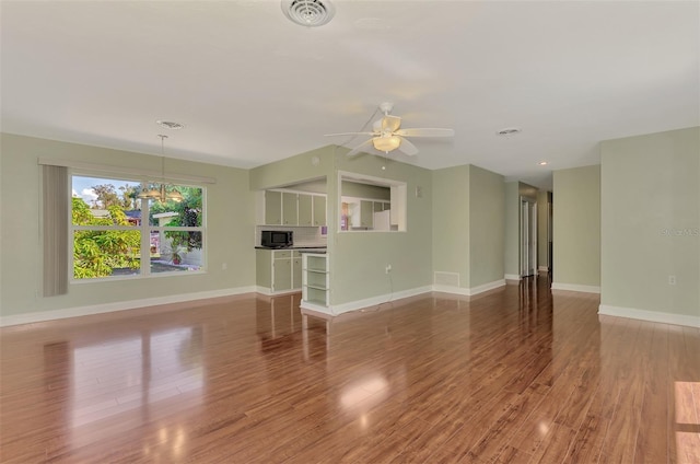 unfurnished living room featuring wood-type flooring and ceiling fan with notable chandelier