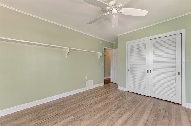 unfurnished bedroom with crown molding, wood-type flooring, a closet, and ceiling fan