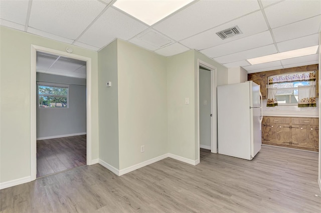 unfurnished room with a drop ceiling and light wood-type flooring