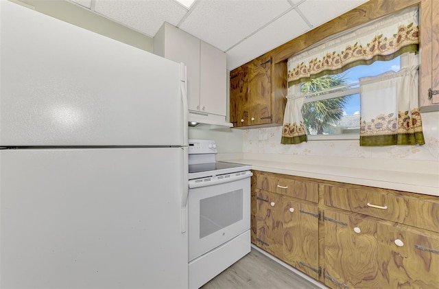 kitchen with light hardwood / wood-style floors, a paneled ceiling, and white appliances