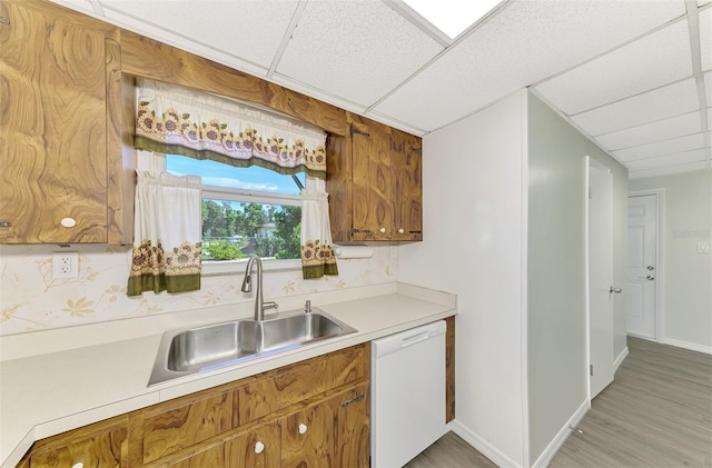 kitchen featuring decorative backsplash, a paneled ceiling, hardwood / wood-style flooring, white dishwasher, and sink