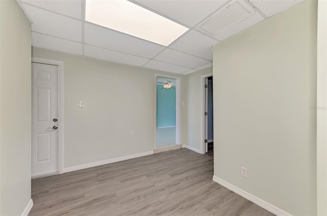 unfurnished room featuring light hardwood / wood-style floors and a paneled ceiling