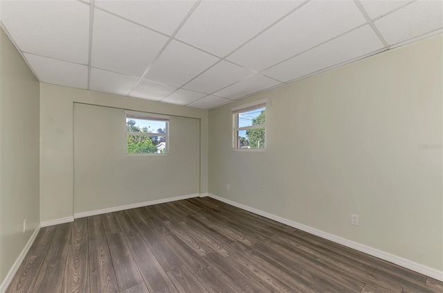 empty room featuring a paneled ceiling and dark hardwood / wood-style flooring