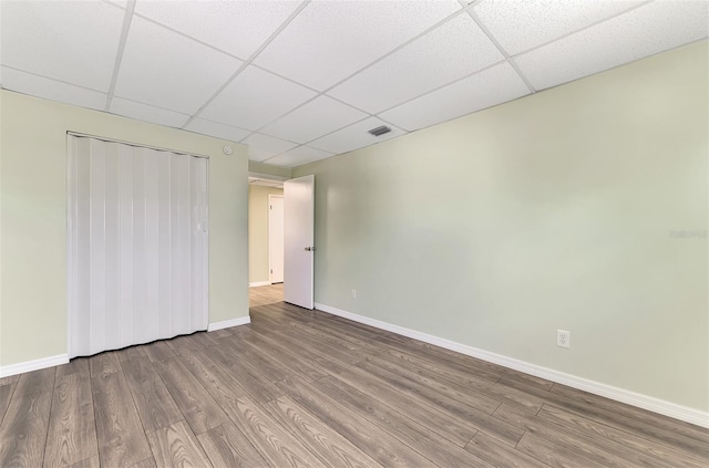 unfurnished bedroom featuring a drop ceiling, hardwood / wood-style flooring, and a closet