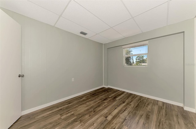 empty room featuring a drop ceiling and dark hardwood / wood-style floors